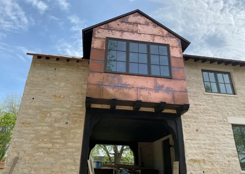 Copper metal panel facade on a stone building for Roof Repair in Maple Grove